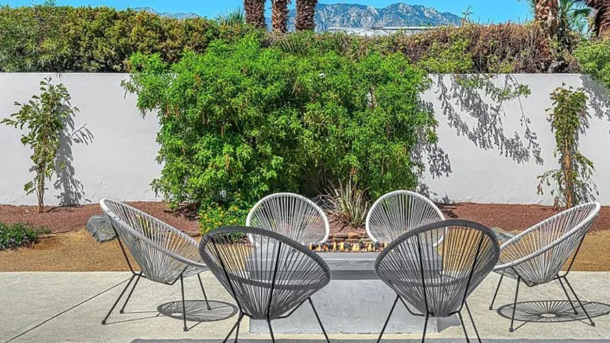 A patio with a firepit surrounded by chairs.