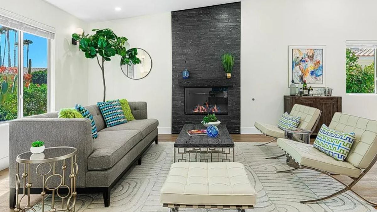 A family room with windows, a houseplant, a fireplace, a painting, a rug, couches, and a coffee table.