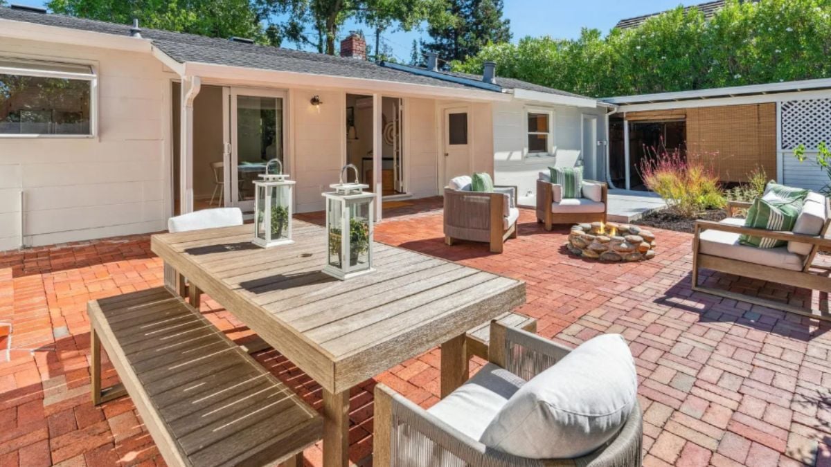 A patio with a table, bench, chairs, and a firepit surrounded by additional chairs and a couch.