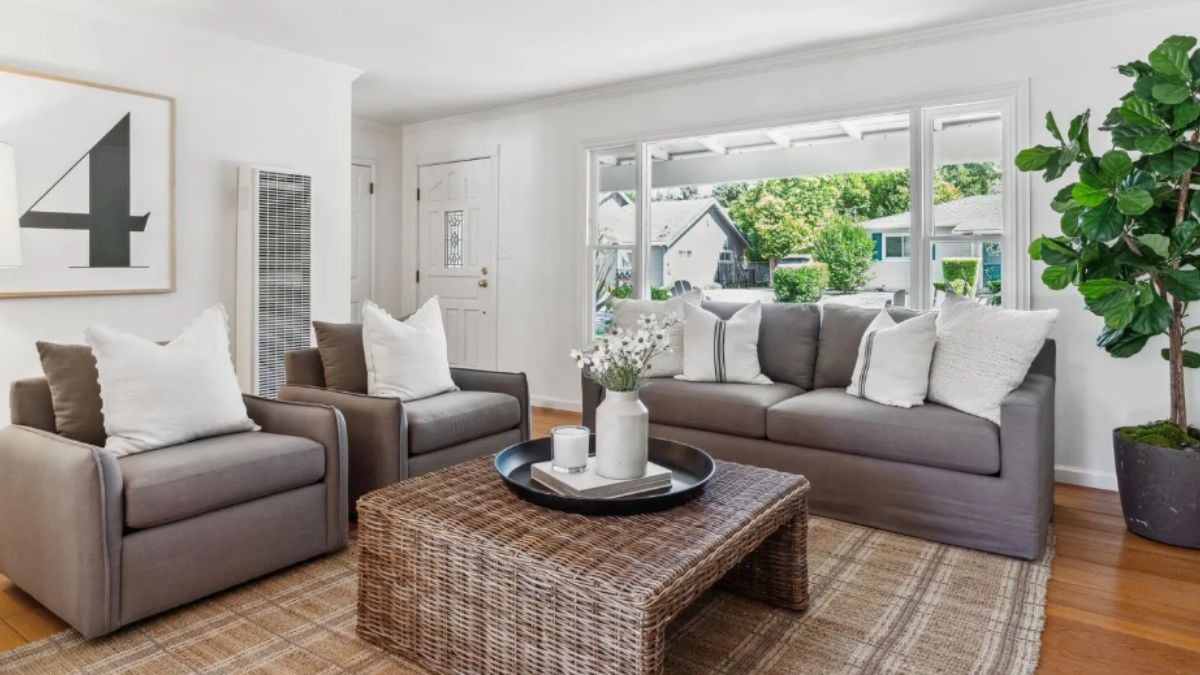 A living room with a houseplant, painting, couches, and a center table.