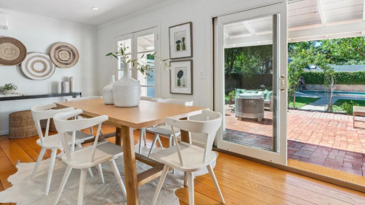 A dining room with a window and a dining table surrounded by chairs.