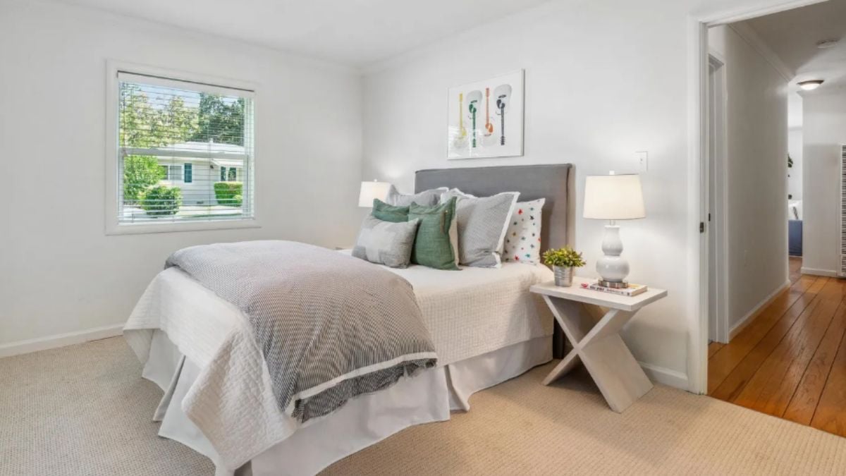 A bedroom with a bed, a window, and a side table.