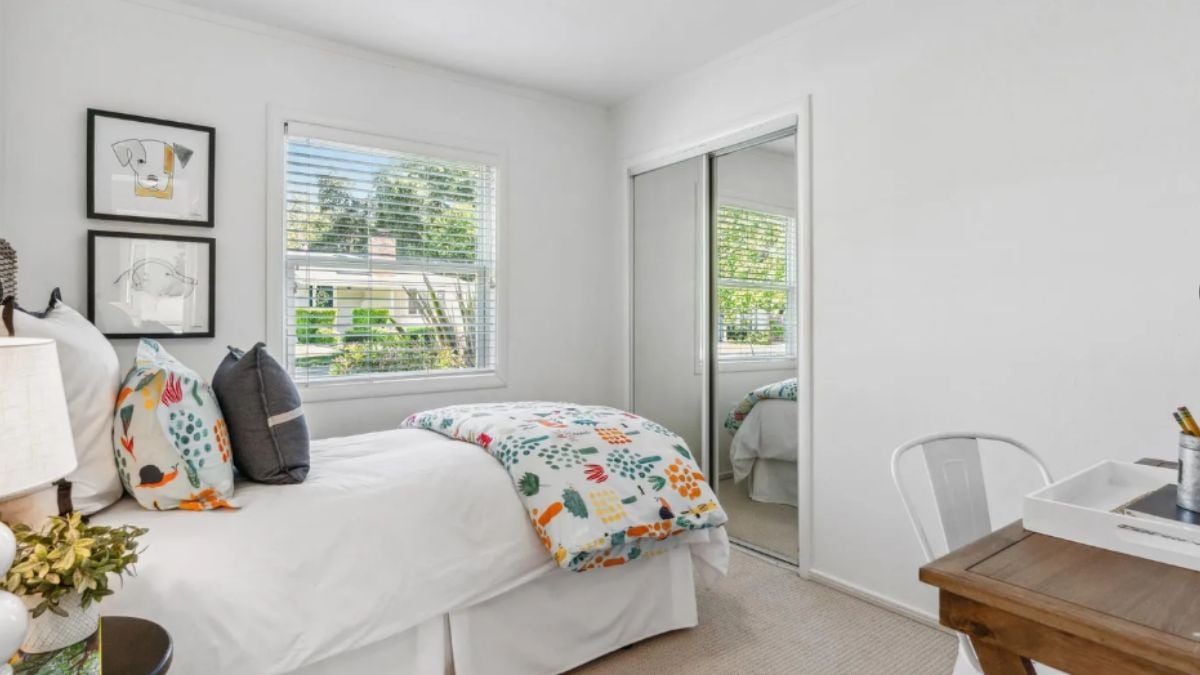 A bedroom with a bed, a window, a desk, and a chair.