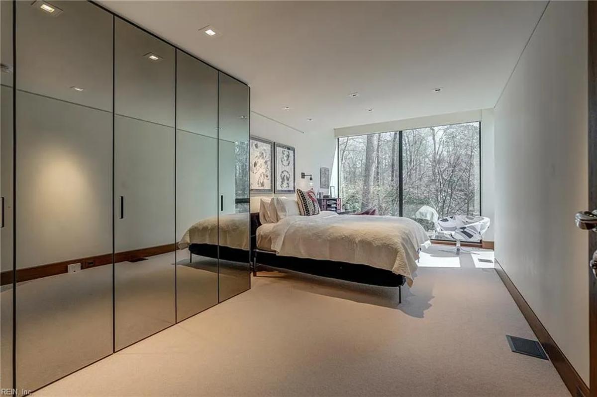 Bedroom with a large bed, glass walls and carpet flooring.