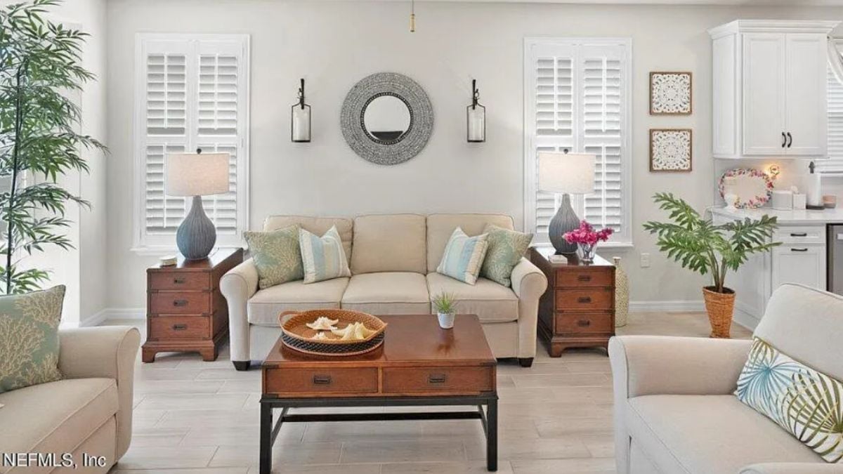 A living room with windows, houseplants, couches, cabinets, and a center table.