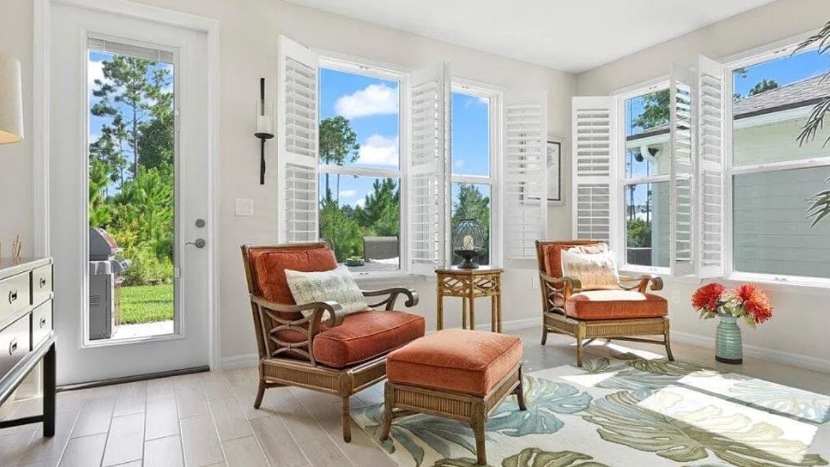 A family room with windows, a cabinet, chairs, and a rug.