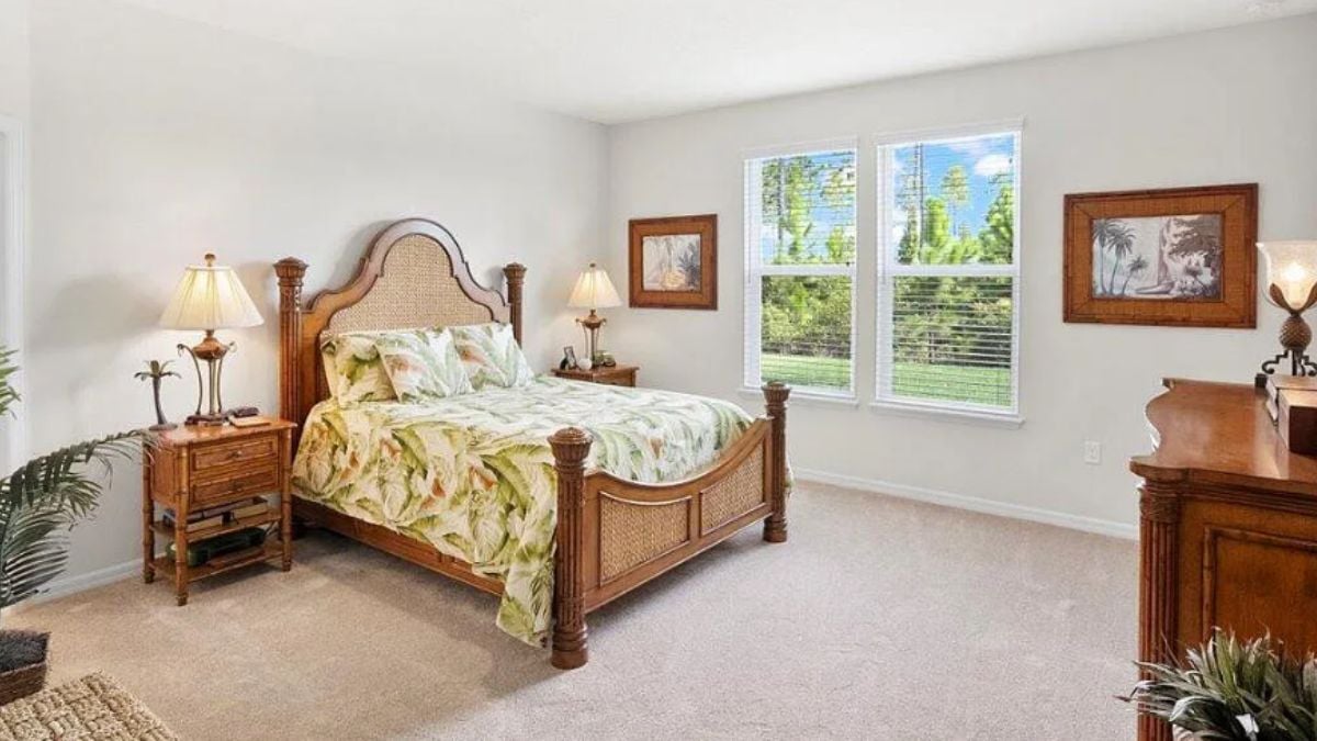 A bedroom with a bed, painting, window, cabinet, and nightstand.