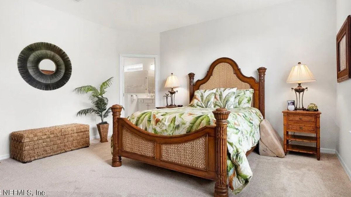 A bedroom with a bed, painting, bench, and nightstand.