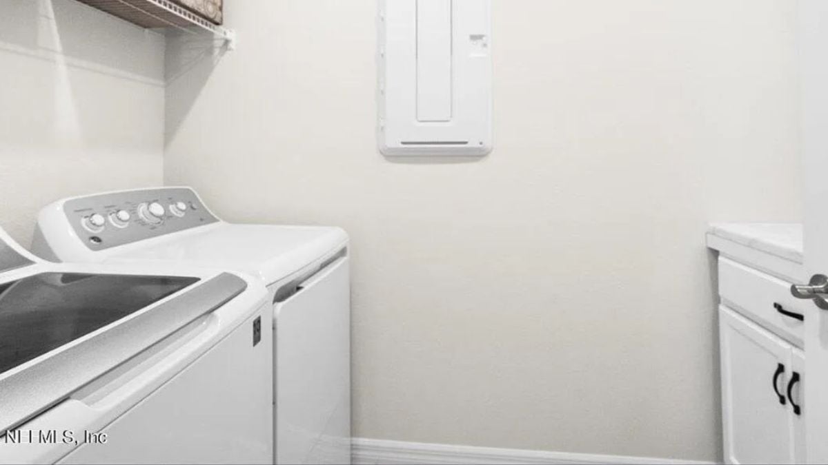 A bathroom with washing machines and a cabinet.