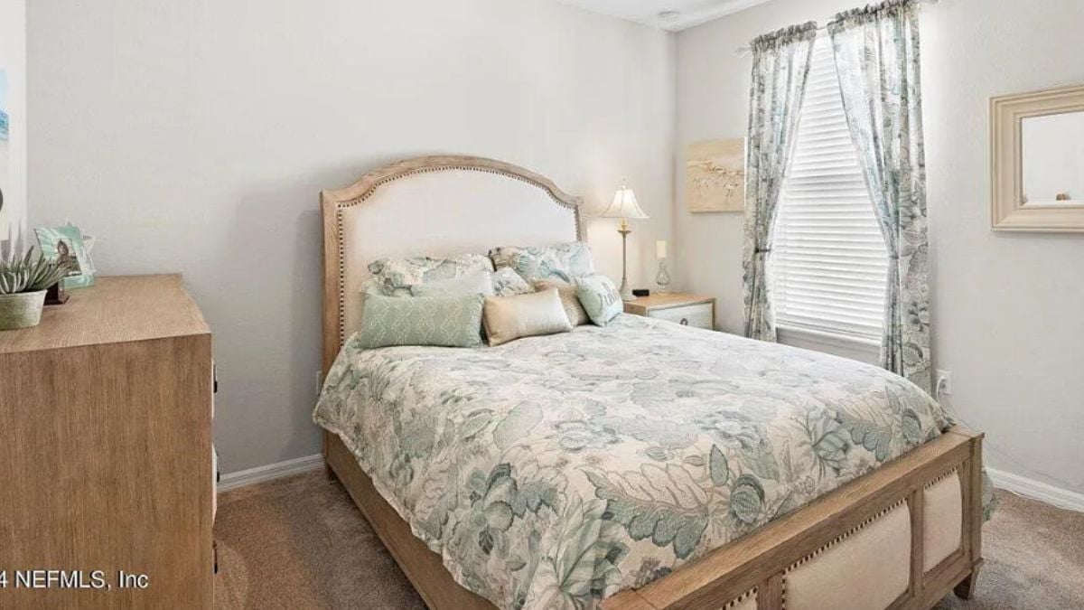 A bedroom with a bed, a nightstand, a window, and a cabinet.