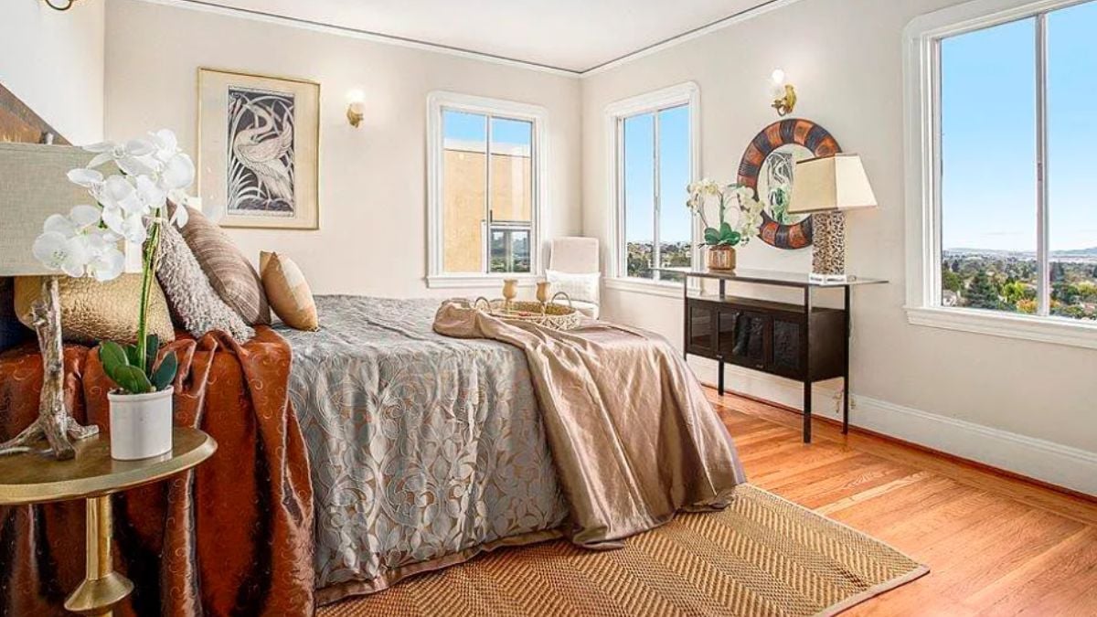 A bedroom with a bed, windows, a desk, and a nightstand.