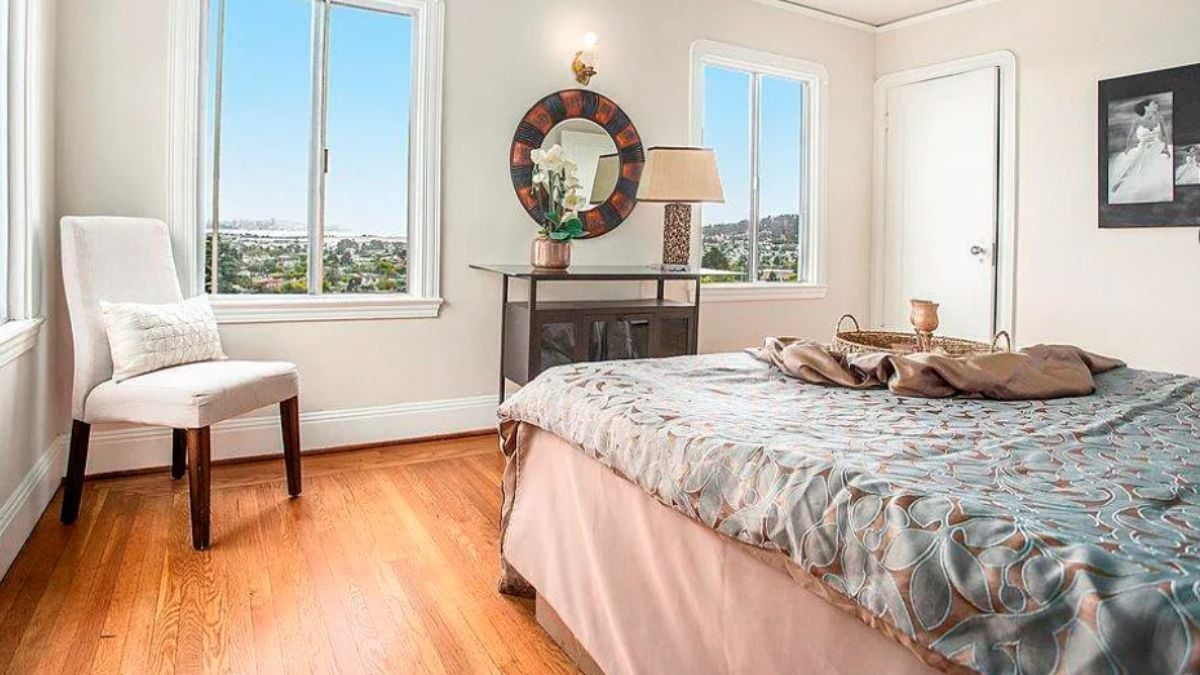 A bedroom with a bed, windows, a chair, and a desk.