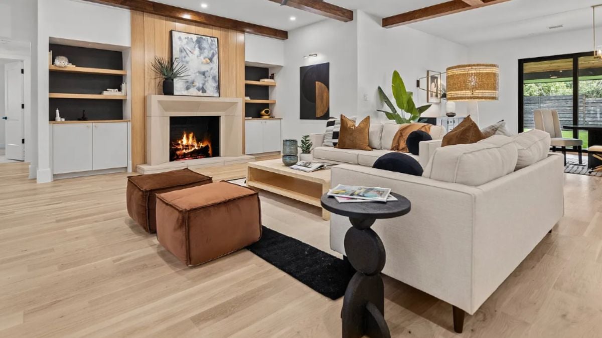 A living room with a fireplace, cabinets, shelves, paintings, chairs, couches, and a center table.