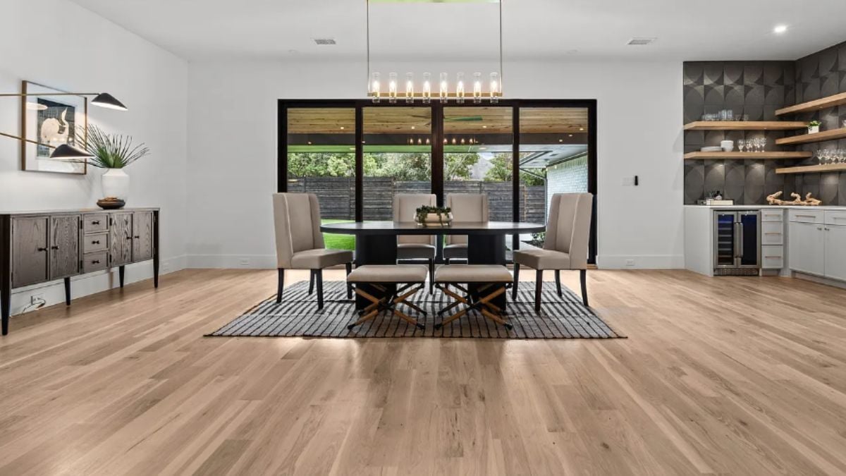 A dining room with a painting, a cabinet, and a dining table surrounded by chairs.