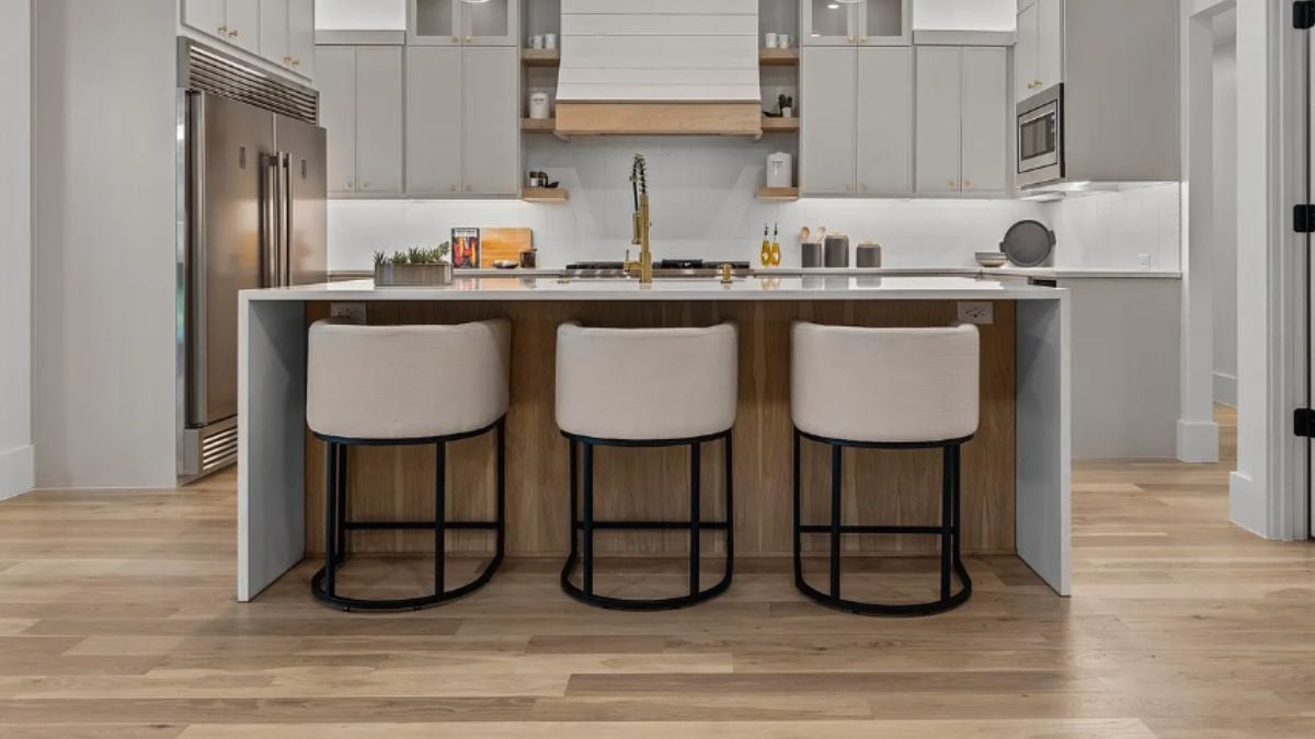 A kitchen with countertops, chairs, a sink, cabinets, and kitchen appliances.
