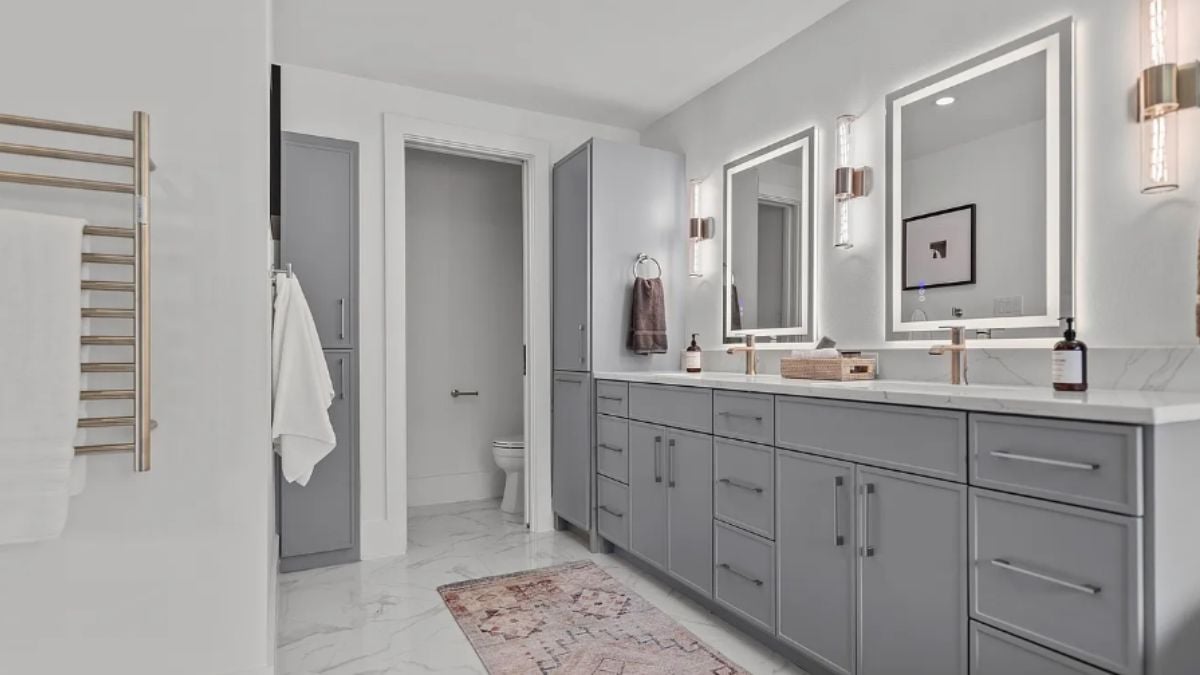 A bathroom with vanities, mirrors, and a cabinet.