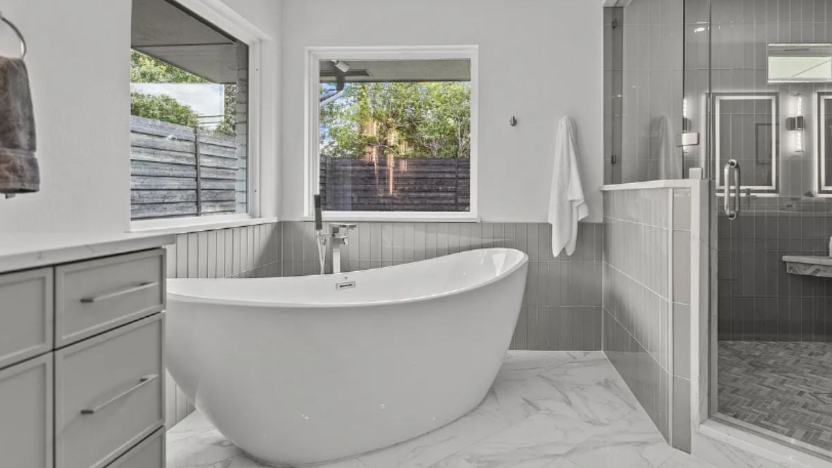 A bathroom with a shower room, windows, and a bathtub.