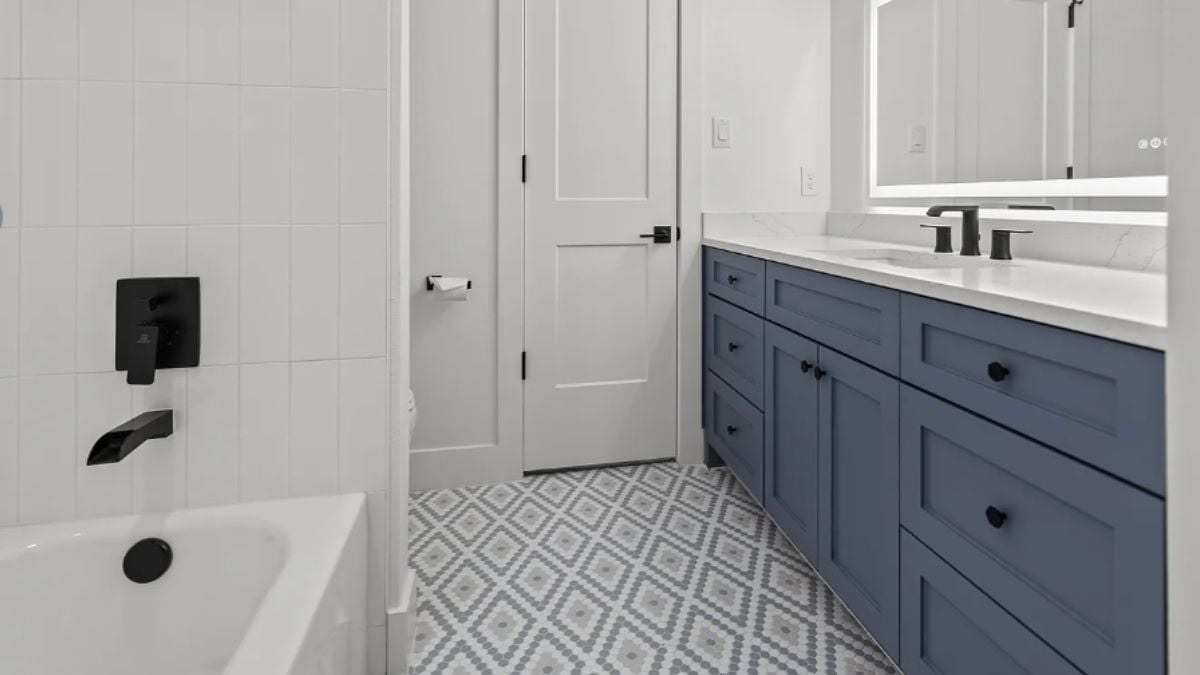 A bathroom with a vanity, a mirror, a cabinet, and a bathtub.