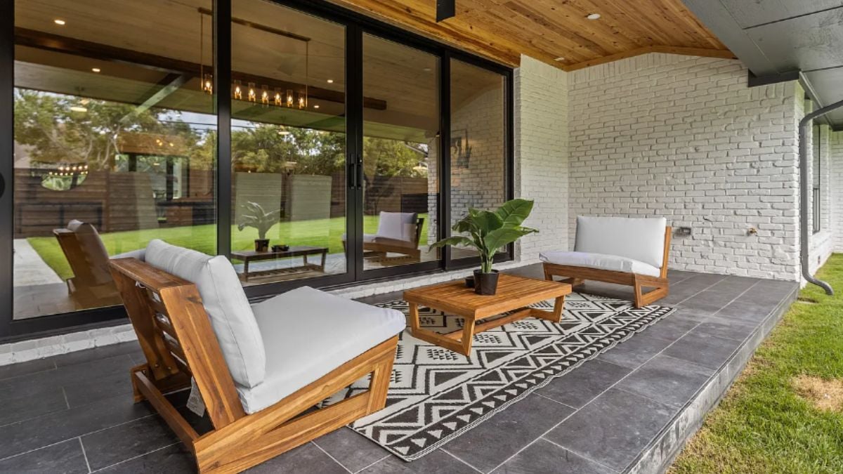 A porch with a rug, chairs, and a center table.