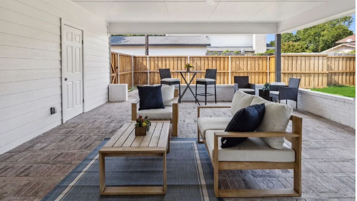 A porch with chairs, a rug, a couch, and coffee tables.