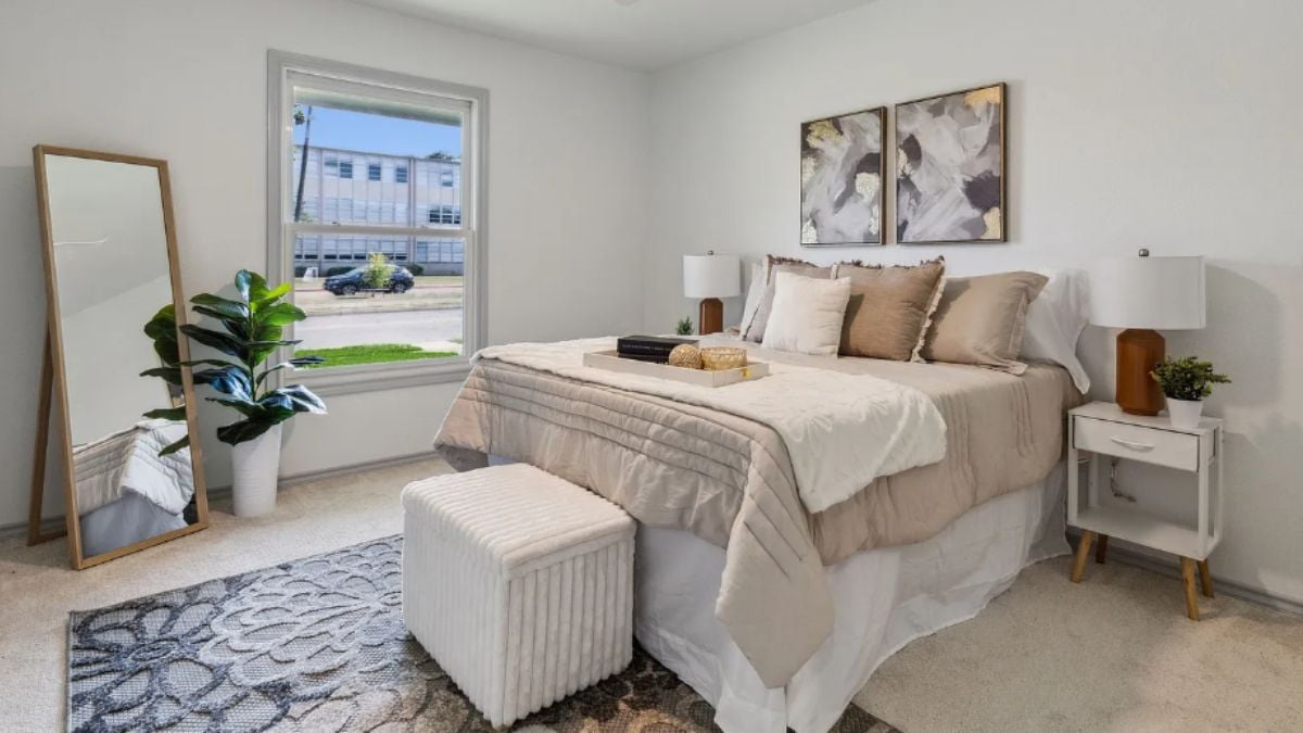 A bedroom with a bed, a window, a painting, nightstands, and a rug.