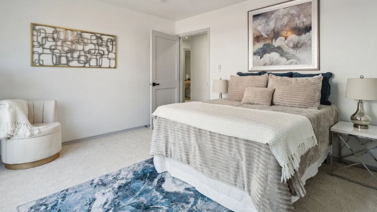 Bedroom with a bed, a painting, a rug, a chair, and a nightstand.