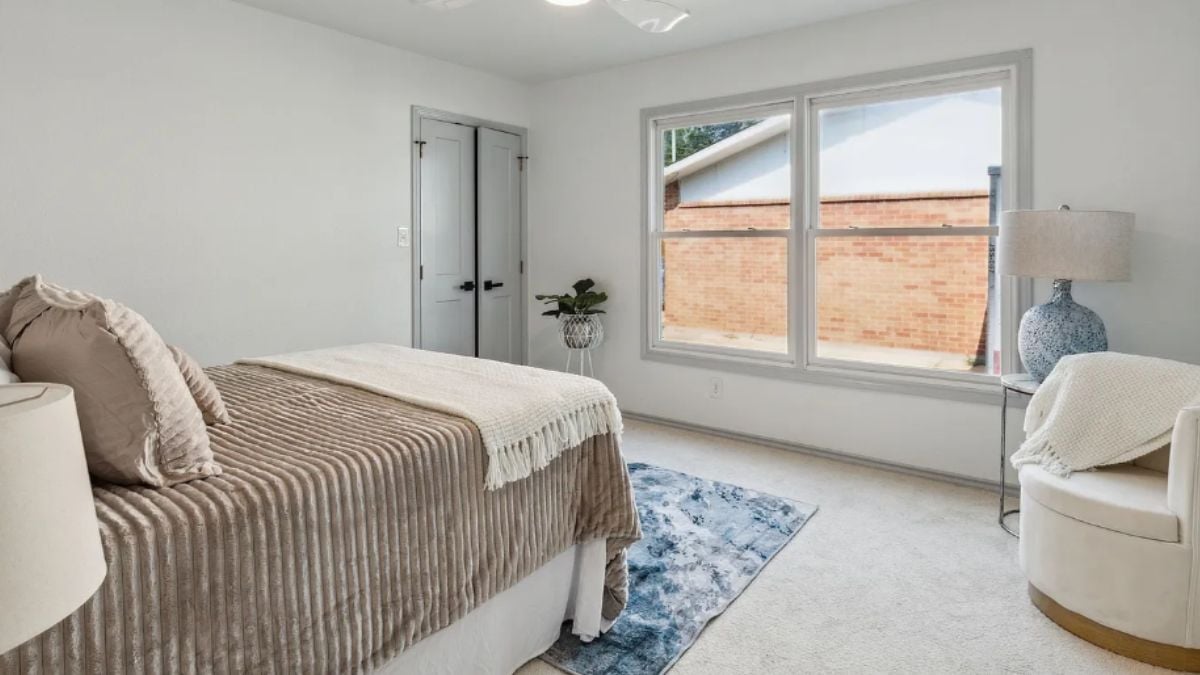 A bedroom with a bed, a chair, and a window.