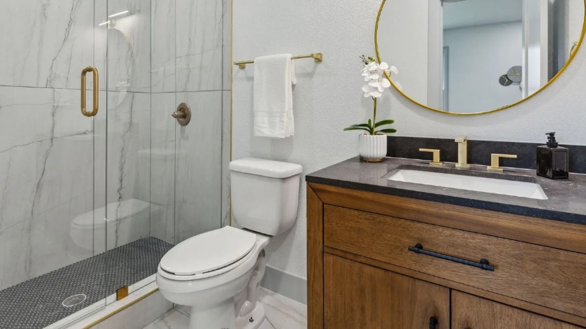 A bathroom with a vanity, a toilet, and a shower room.