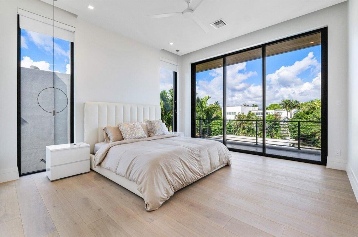 Bedroom with hardwood floor and a balcony.