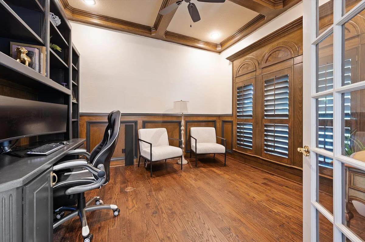 Office with a black desk, louvered windows, and a coffered ceiling.