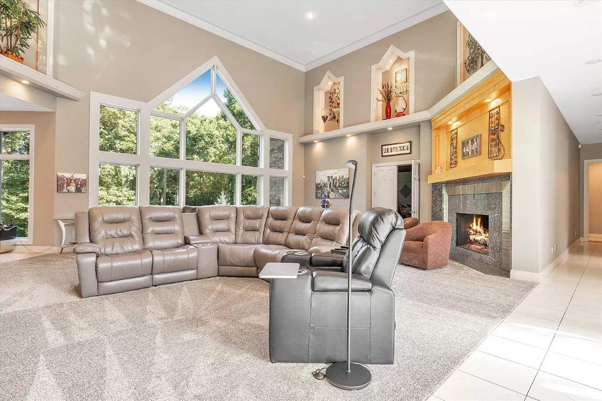 Living room with couches, carpet flooring and a fireplace.