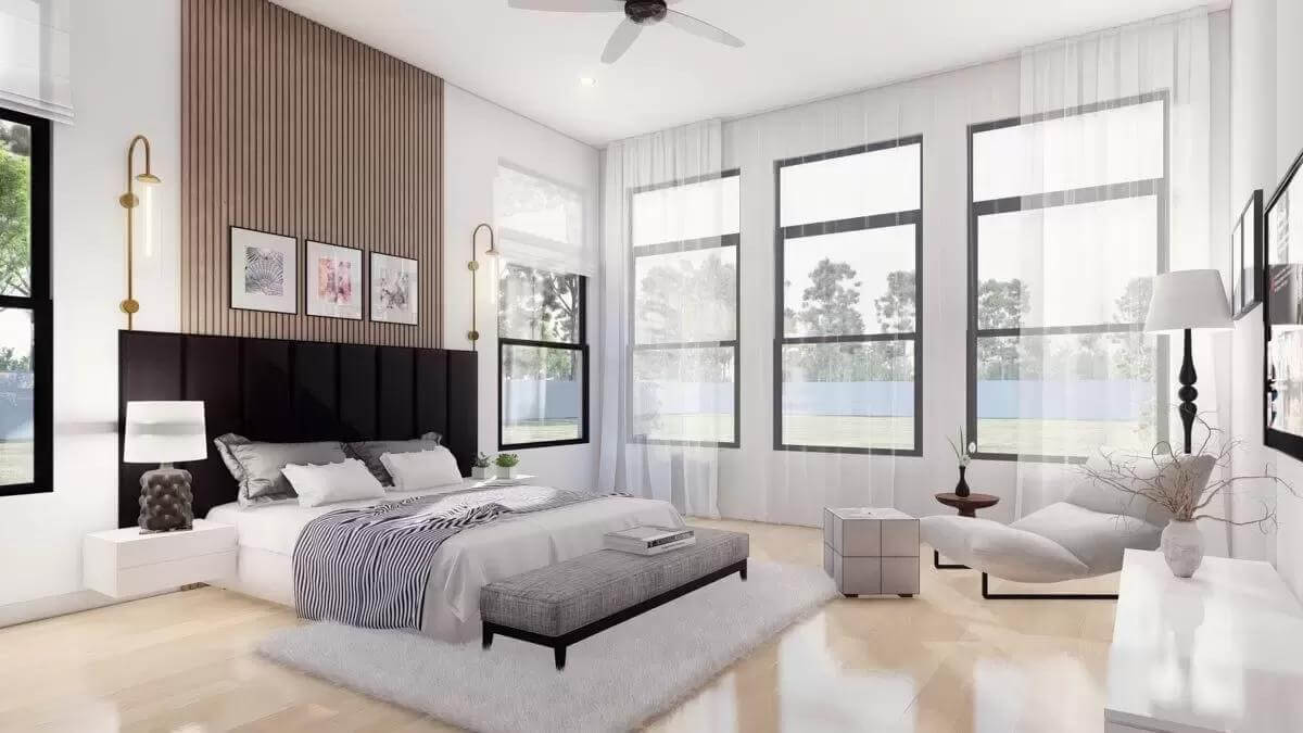 Primary bedroom with a custom bed, a lounge chair, and large windows dressed in sheer curtains.