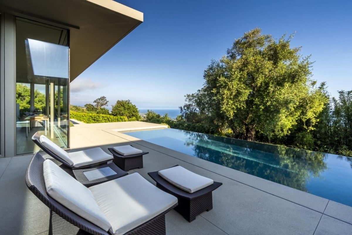 A swimming pool with chairs on the poolside.