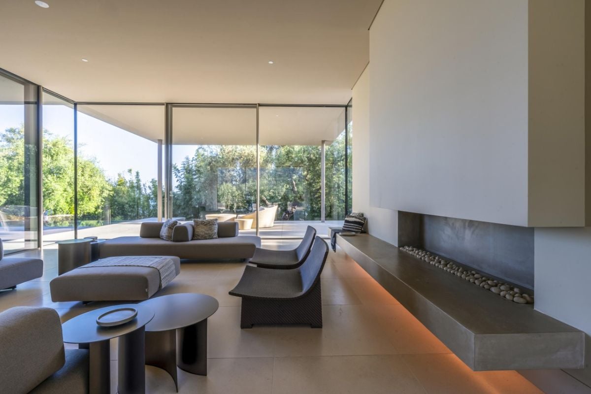 A living room with floor-to-ceiling windows, gray couches, chairs, and an ottoman.