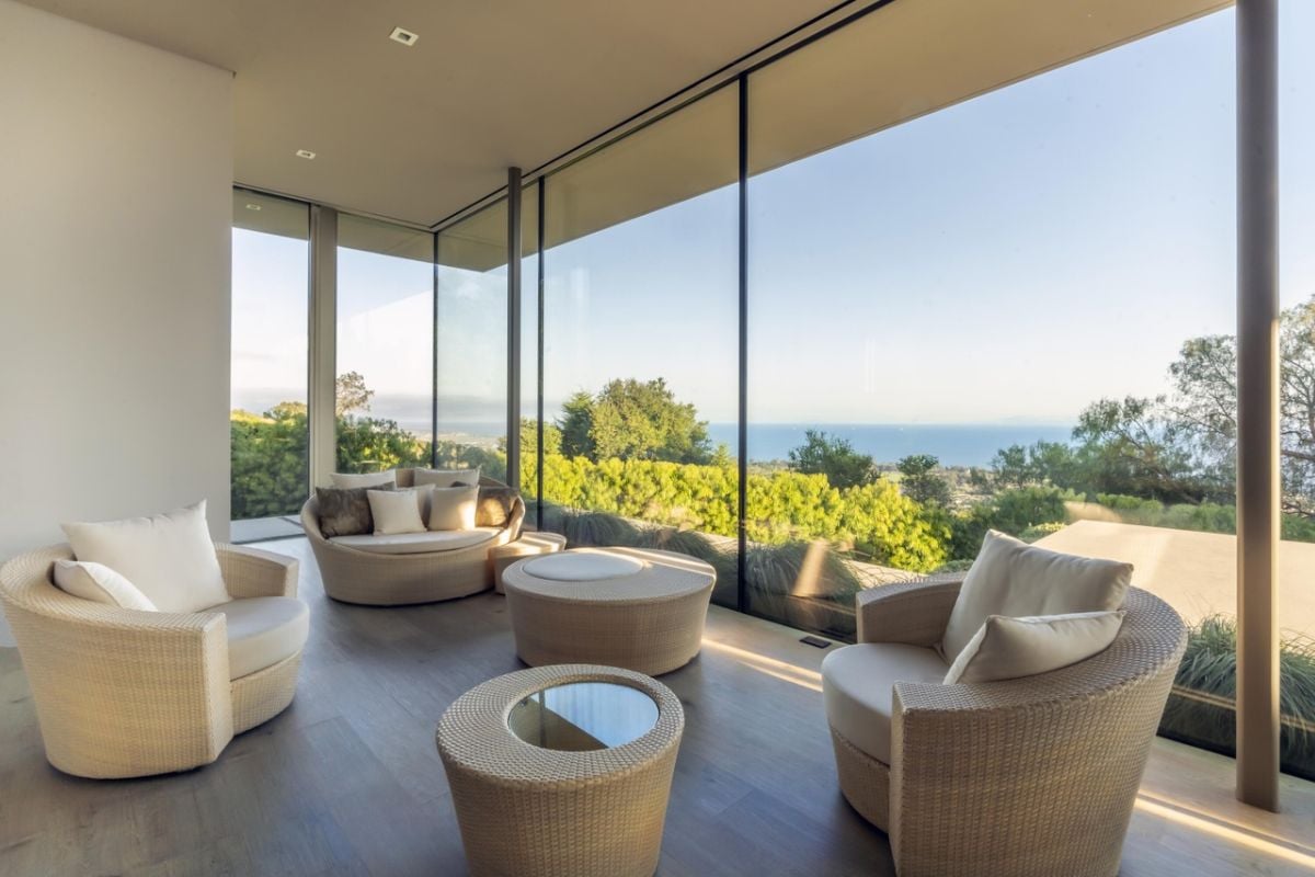 A living room with floor-to-ceiling windows, couches, and coffee tables.