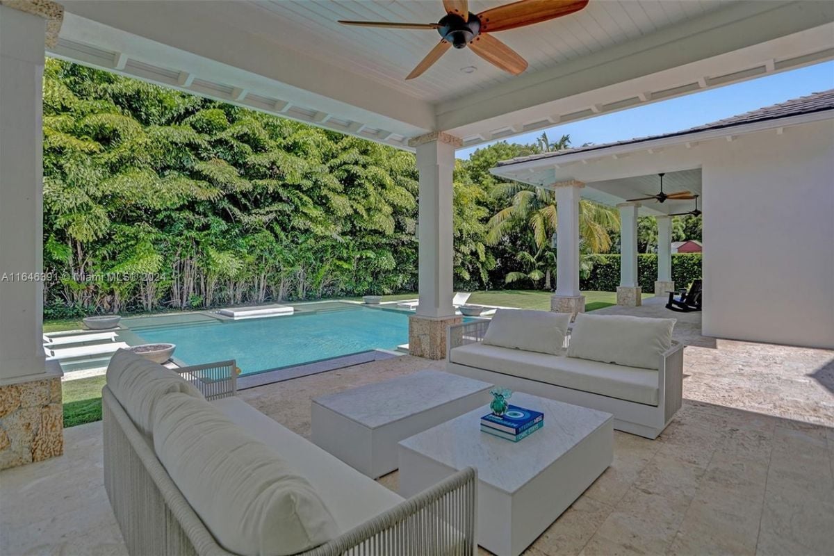 A porch with a ceiling fan, couches, and center tables.