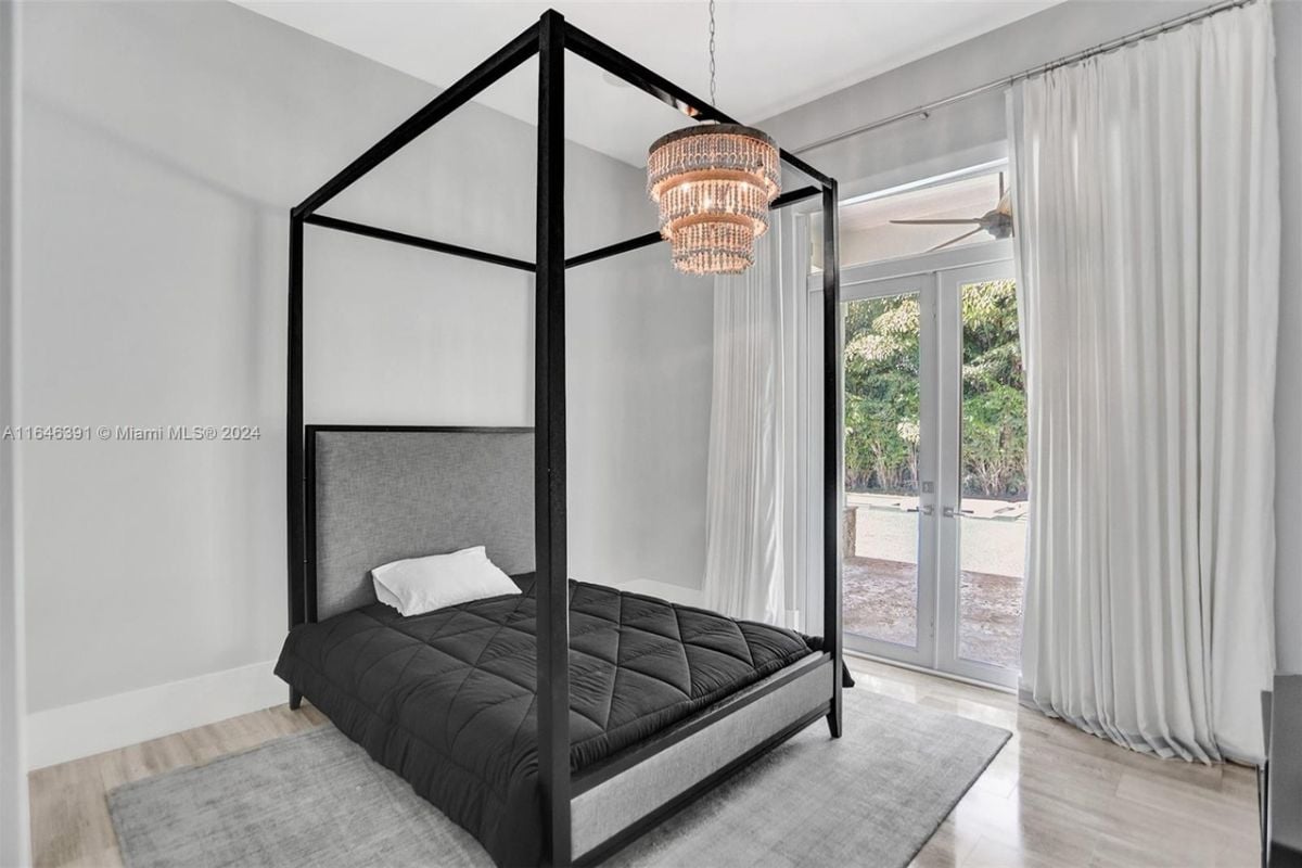 A bedroom with a canopy bed, rug, and chandelier.