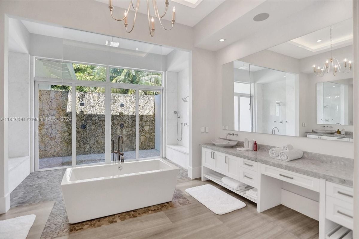 A bathroom with a vanity, mirror, drawers, and bathtub.