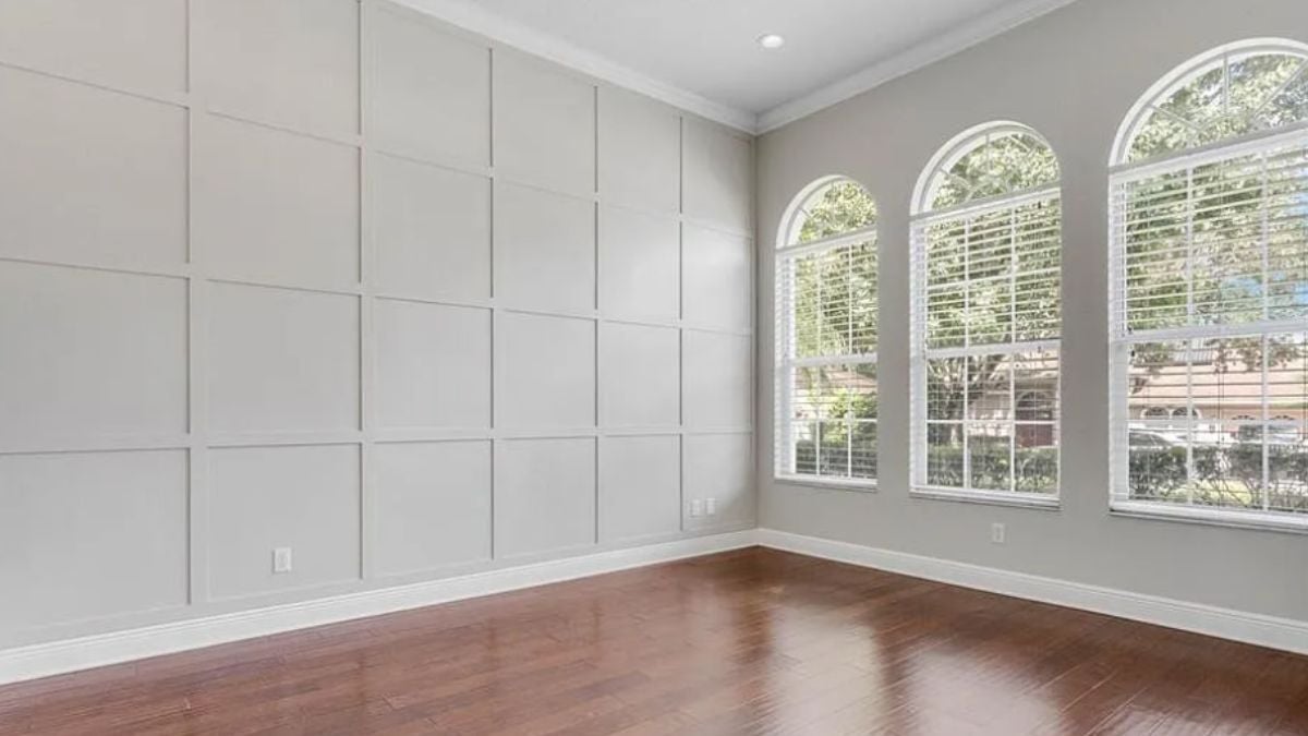 A living room with wooden floors, white walls, and windows.