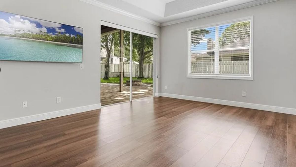 A bedroom with a TV, wooden floor and a window.