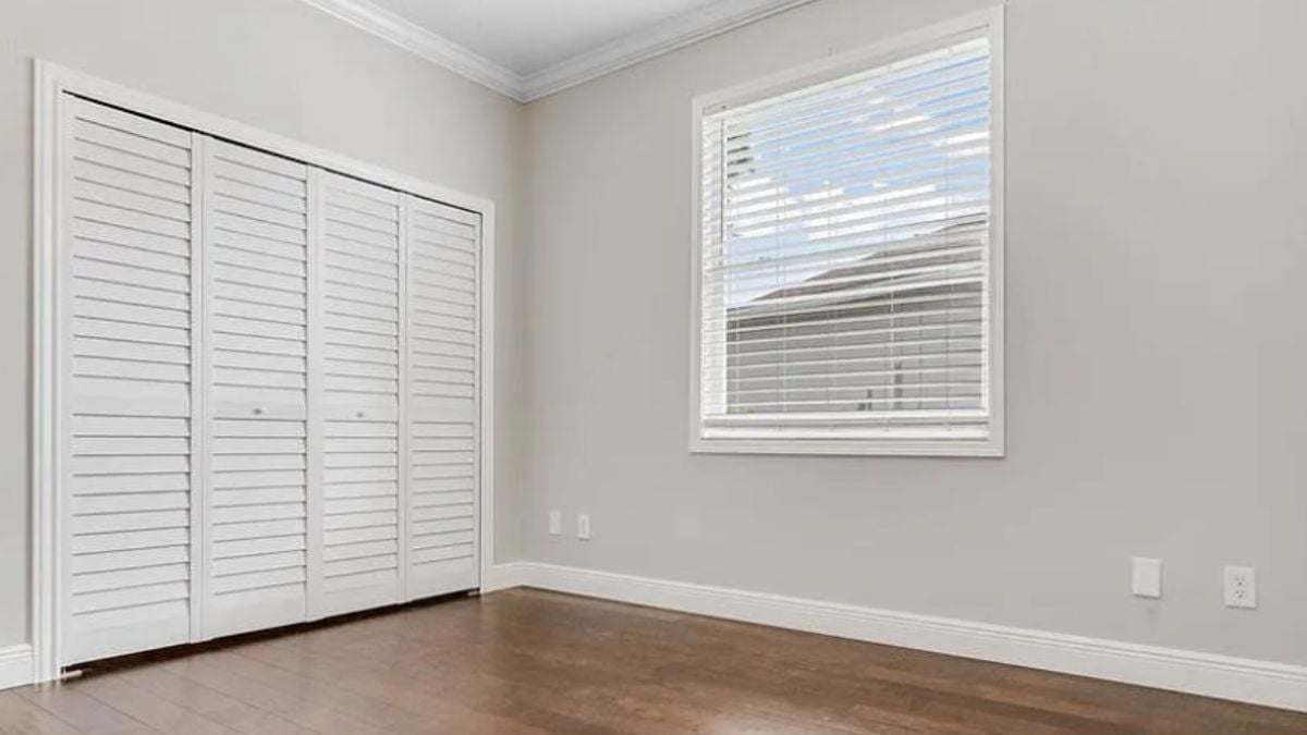A bedroom with a wooden floor and a window.