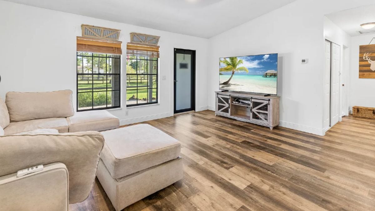 A living room with windows, a TV, and a couch.