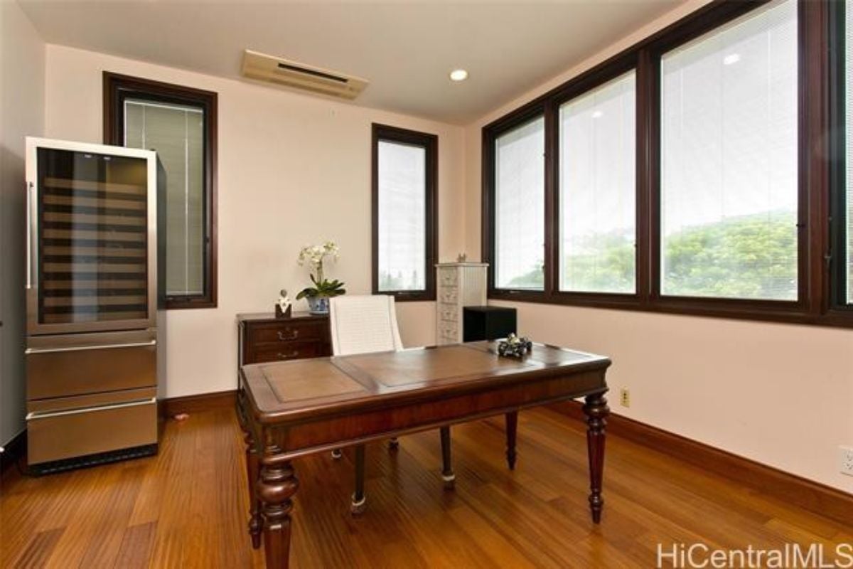 A home office with windows, a cabinet, desk, and chair.