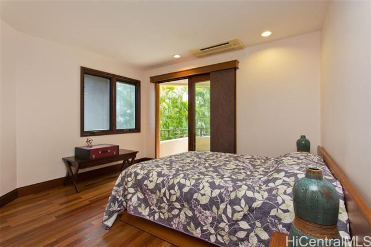 A bedroom with a bed, wooden floor, and window.