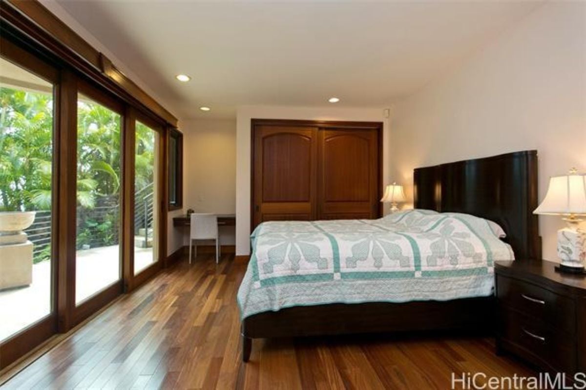 A bedroom with a bed, nightstand, and desk with a chair.