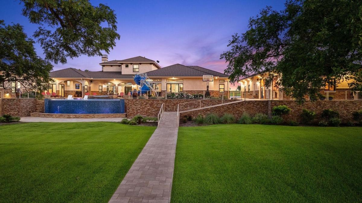 Rear view of the mansion with a large green lawn.