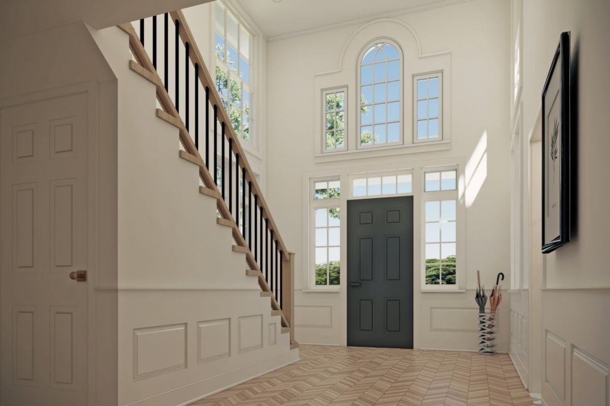 A foyer with a high ceiling, windows, and a staircase.