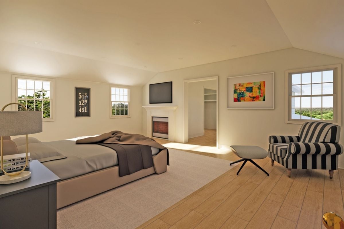 A bedroom with a bed, a rug, a nightstand, windows, a TV, a fireplace, a chair, and a coffee table.