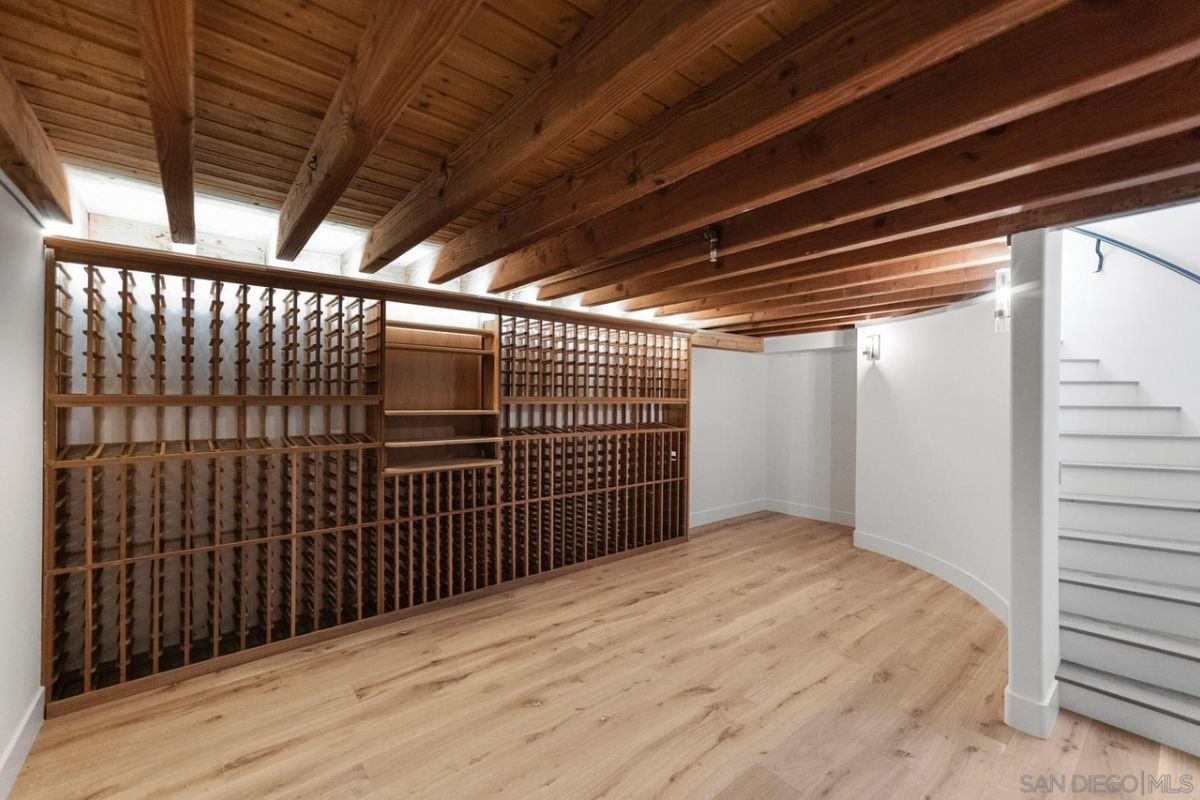A wine cellar with an exposed beam ceiling and wine racks.