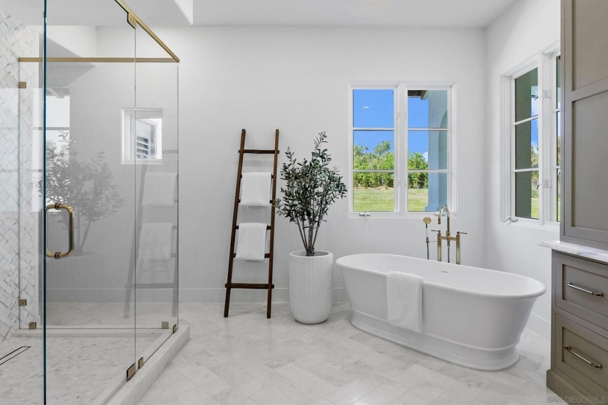 A bathroom with windows, a bathtub, and a glass shower.